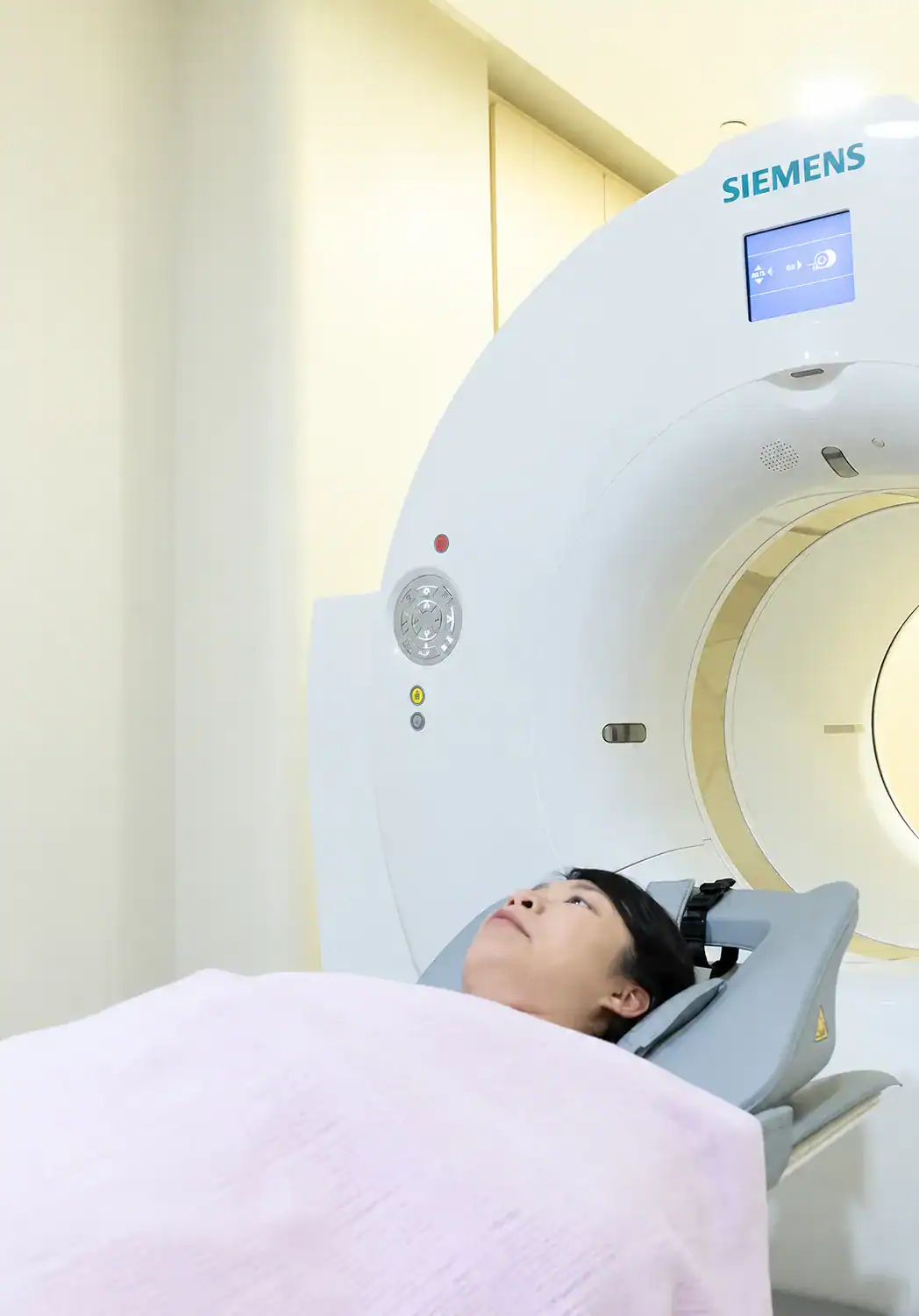 A patient undergoing a CT scan in a modern medical imaging facility equipped with a Siemens scanner.